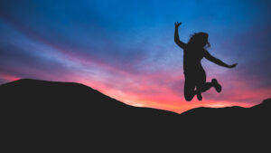 a woman doing a jump shot pose during sunset